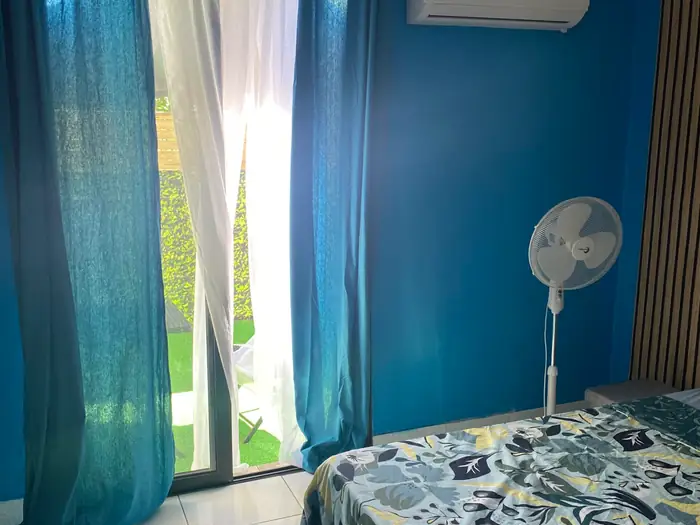 Chambre bleue ouverte sur la terrasse, lit habillé de motifs végétaux