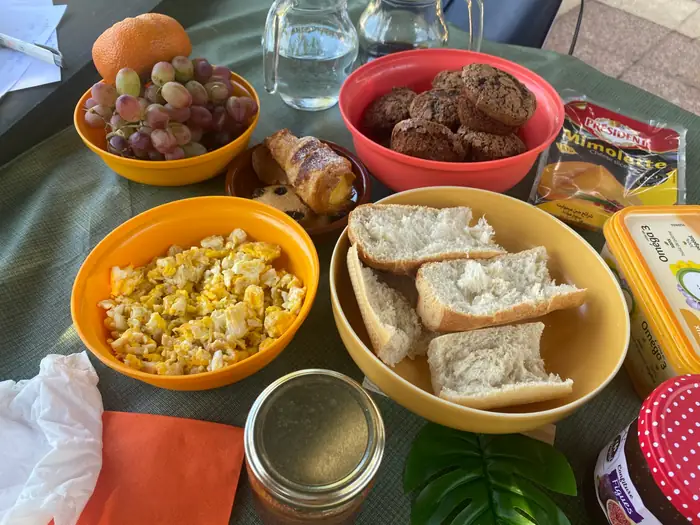 Table du petit-déjeuner : pains, confitures, jus d'orange et yaourts